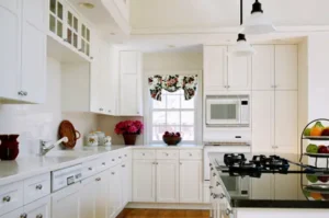Photograph of a kitchen with refinished cabinets in white.